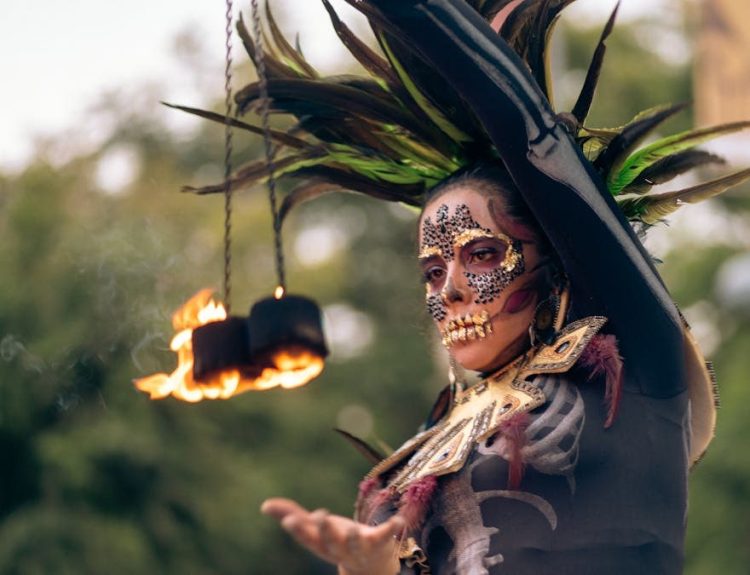 A performer in Catrina costume and makeup spins fire outdoors in Mexico City.